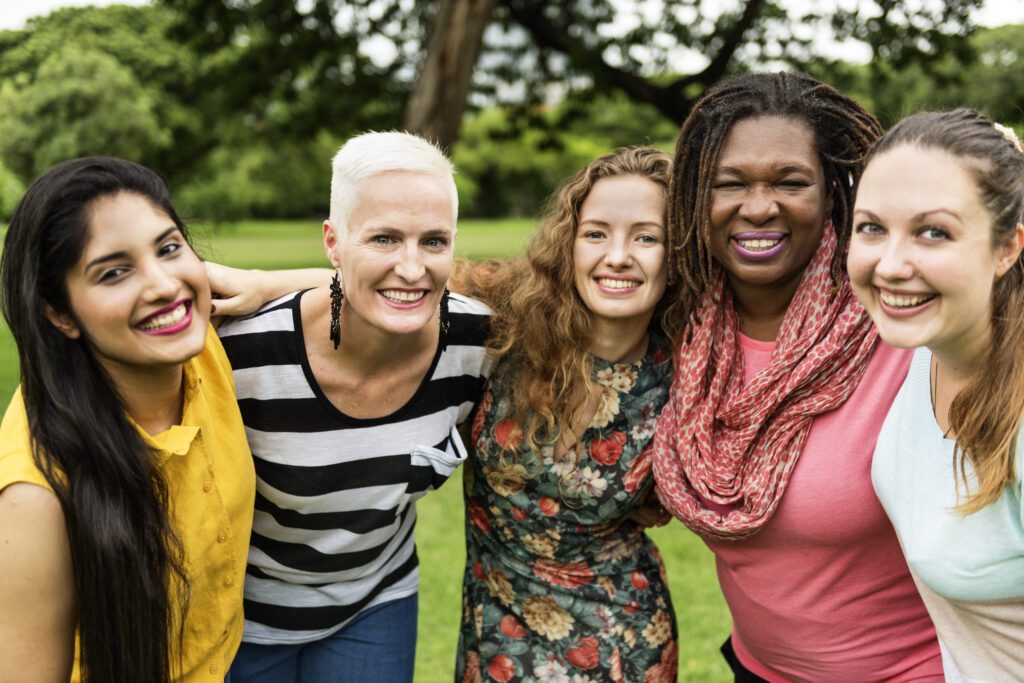 Intergenerational and ethnically diverse group of women embracing and forming a line while celebrating recovery over the adverse effects of trauma.