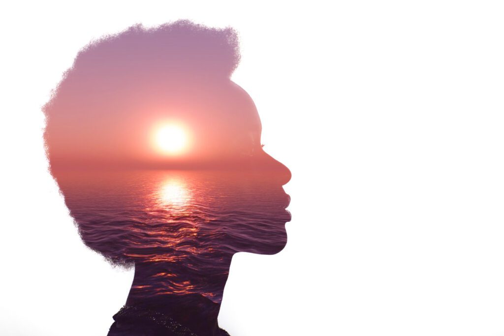 African American woman silhouette with the sun embedded reflecting off of a body of water - the sea
